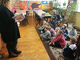dzieci słuchają książki czytanej przez bibliotekarkę