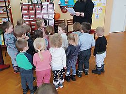 dzieci słuchają bibliotekarki i podnoszą ręce w górę
