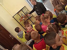 dzieci oglądające wystawę muzealną i słuchające przewodnika