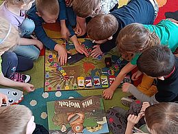 dzieci grają w grę planszową na dywanie