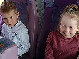 chłopiec i dzieczynka siedzą w autobusie i uśmiechają się do obiektywu
