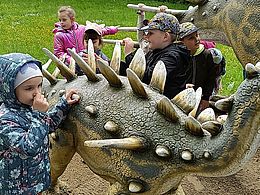 dzieci dotykają makiety dinozaura