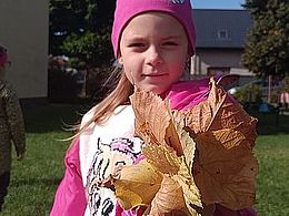 dziewczynka trzyma w ręce bukiet liści