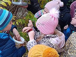 Dzieci wyrzucają ziarenka do karmnika 