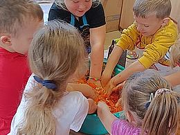 Dzieci mieszają w misce starte marchewki i kapustę 