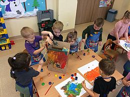 Dzieci wspólnie malują pudełko farbami
