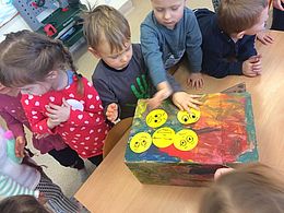 dzieci naklejają na pudełku samoprzylepne buźki z różnymi minami