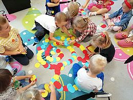 Dzieci układające ślimaka z kropek na dywanie