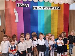 dzieci pozują na tle tęczowej dekoracji