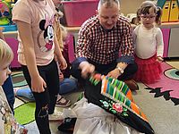 Dzieci oglądają stroje pokazywane przez dorosłego 