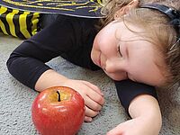 Dziewczynka leży obok jabłka 