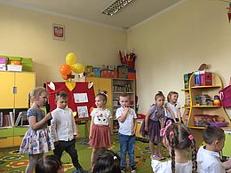 sześcioro dzieci stoi na środku sali, dziewczynka trzyma mikrofon