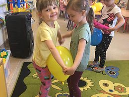 Dzieci stoją parami i trzymają balony swoimi brzuchami 