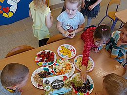 Dzieci wybierają swoje ulubione owoce z talerzyków i je zjadają