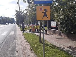 dzieci i nauczycielka stoją w parach przed przejściem dla pieszych