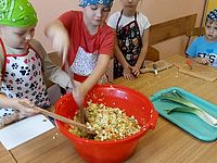 Dzieci mieszające sałatkę w dużej czerwonej misce