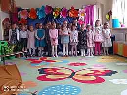 dzieci stoją w dwurzędzie na tle dekoracji
