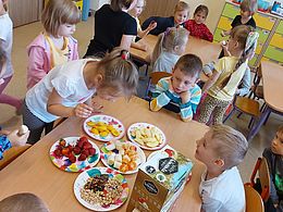 Dzieci wybierają z talerzyków ulubione owoce 