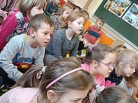 Dzieci siedzą na dywanie i słuchają 