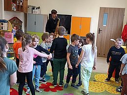 Dzieci tańczą, muzyk gra na saksofonie 