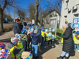 Dzieci z niebieskimi emblematami rozmawiają z kobietą 