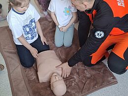 Dziewczynka wykonuje masaż serca na manekinie