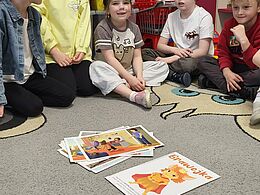 Dzieci siedzą przed kolorowymi kartkami