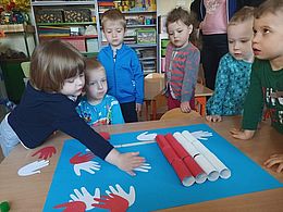 Dzieci odciskają ręce na fladze Polski 