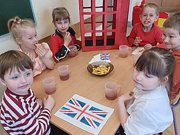 Dzieci siedzą przy stolikach zastawionych frytkami 